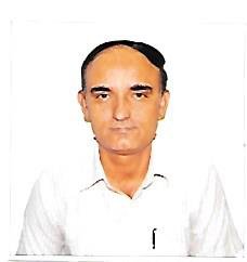 Portrait of Dr. Kapoor wearing traditional attire with academic books in background